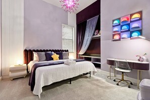 A modern bedroom with a bed, bedside table, and a desk with a chair. - 15BR A Tribute to Animation (6061PG) (Orlando)