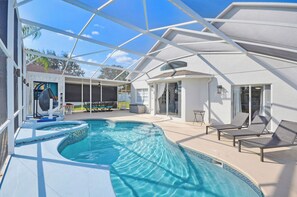 Un área de piscina con un patio de cristal, sillas de descanso y una bañera de hidromasaje.