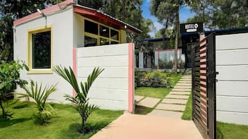 A hotel entrance with a gated driveway, a satellite dish, and a sign indicating it's a company-serviced hotel.