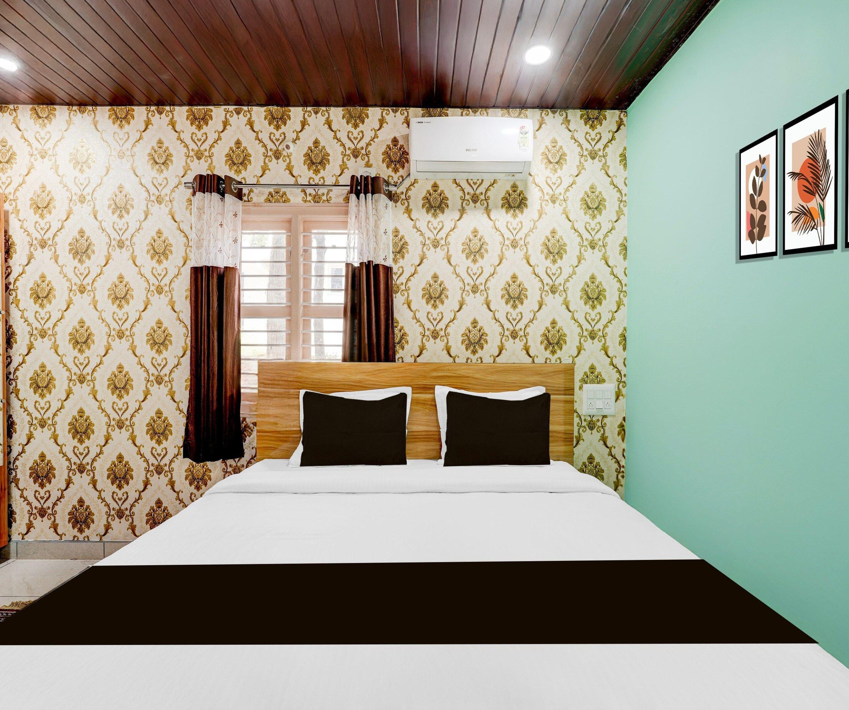 A hotel room with a bed, curtains, an air conditioning unit, and a wall with framed artwork.
