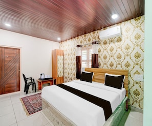 A hotel room with a bed, a desk, a chair, and a wardrobe. - Classic Kaveri Homestay (Shrirangapattana)