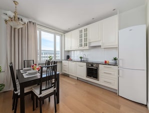 A modern kitchen with white cabinets, a built-in oven, and a stainless steel refrigerator. - Apartment With Skyline Balcony (Warsaw)