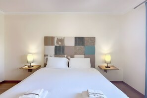 A hotel room with a large bed, two bedside tables, and a headboard with a decorative panel. - Walking distance to vilamoura marina! apartment with pool and garden (Quarteira)