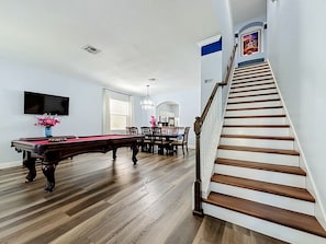 A spacious room with a pool table, dining area, and a staircase. - 6BR Disney Villa, Private Pool/Spa + Resort Access (Kissimmee)