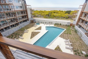 Area piscina con numerosi lettini, una vasca idromassaggio circolare e vista sull'oceano.