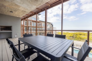 Un balcone con tavolo e sedie, vista su un edificio e cielo sereno.