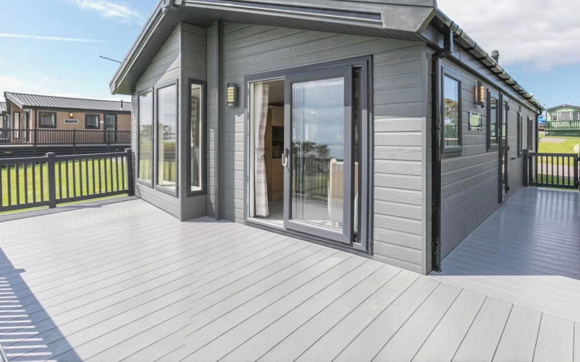 A modern house with a deck, large sliding glass doors, and a fenced yard.