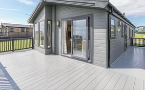Une maison moderne dotée d’une terrasse, de grandes portes-fenêtres coulissantes et d’une cour clôturée.