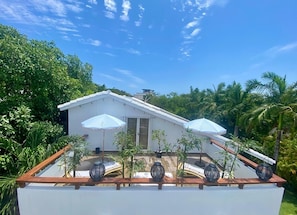 Une maison moderne, dotée d’un toit plat, entourée d’une végétation luxuriante et de palmiers.