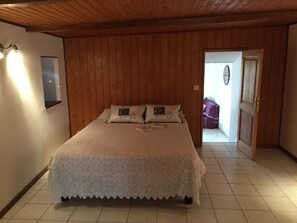 A bedroom with a wooden ceiling, a bed with a white bedspread, and a door leading to another room. - Cottage 'Joannet' with Mountain View, Private Terrace and Wi-Fi (Lamastre)