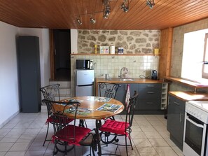 A compact kitchen with a dining area, featuring a refrigerator, stove, and a microwave. - Cottage 'Joannet' with Mountain View, Private Terrace and Wi-Fi (Lamastre)