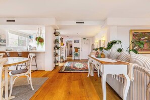 A modern living room with a dining area, wooden flooring, and a colorful rug. - Crafted with Soul A Leafy Boho Escape by the Sea (Port Melbourne)