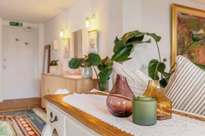 A room with a wooden table, a white drawer, a patterned rug, and a green vase. - Crafted with Soul A Leafy Boho Escape by the Sea (Port Melbourne)