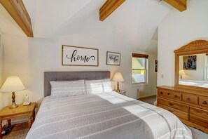 Een slaapkamer met een bed, twee nachtkastjes, een kaptafel, een spiegel en een muur met een bord waarop 'home' staat.