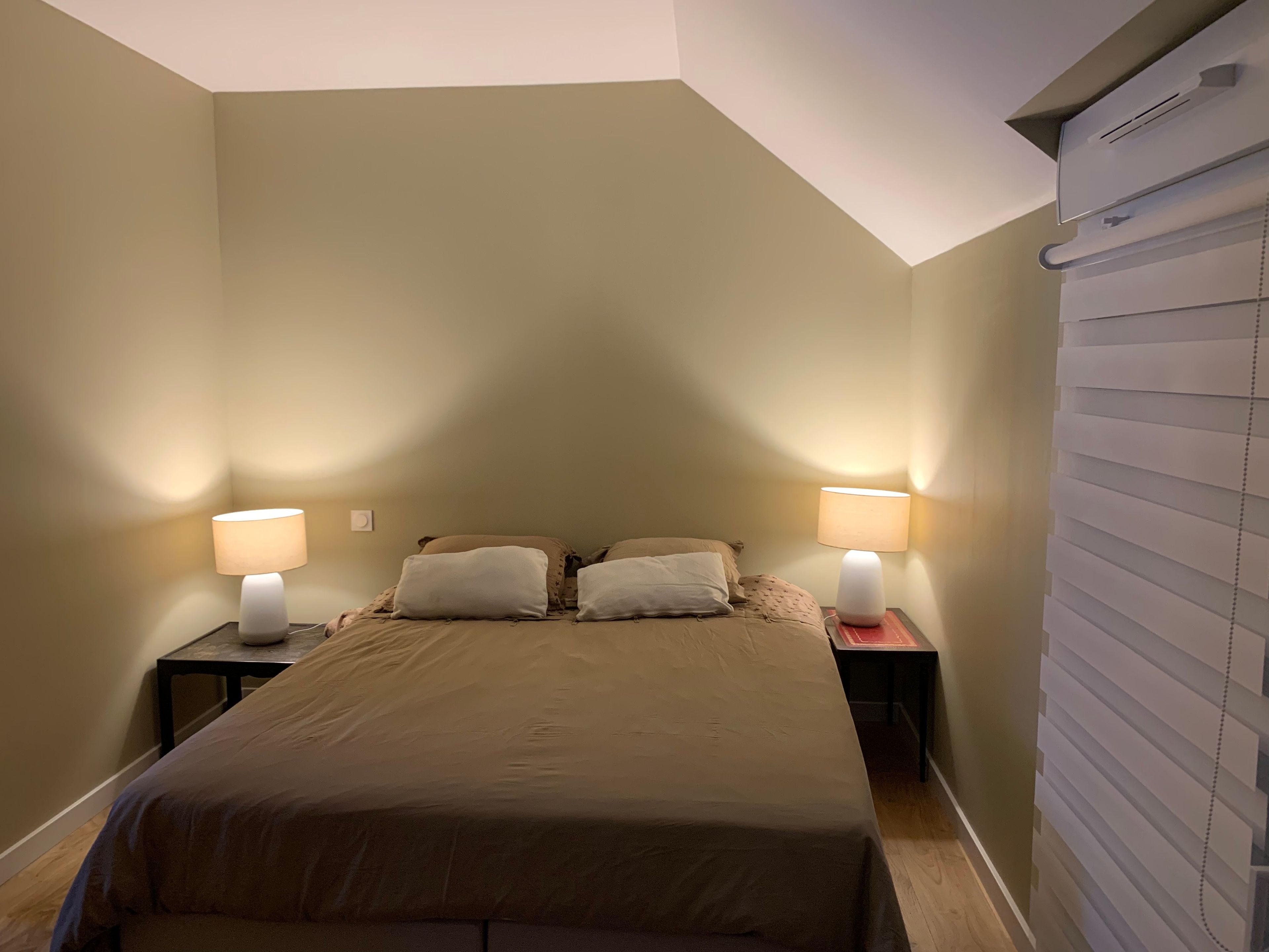 Une chambre à coucher avec un lit, deux tables de chevet et des lampes.