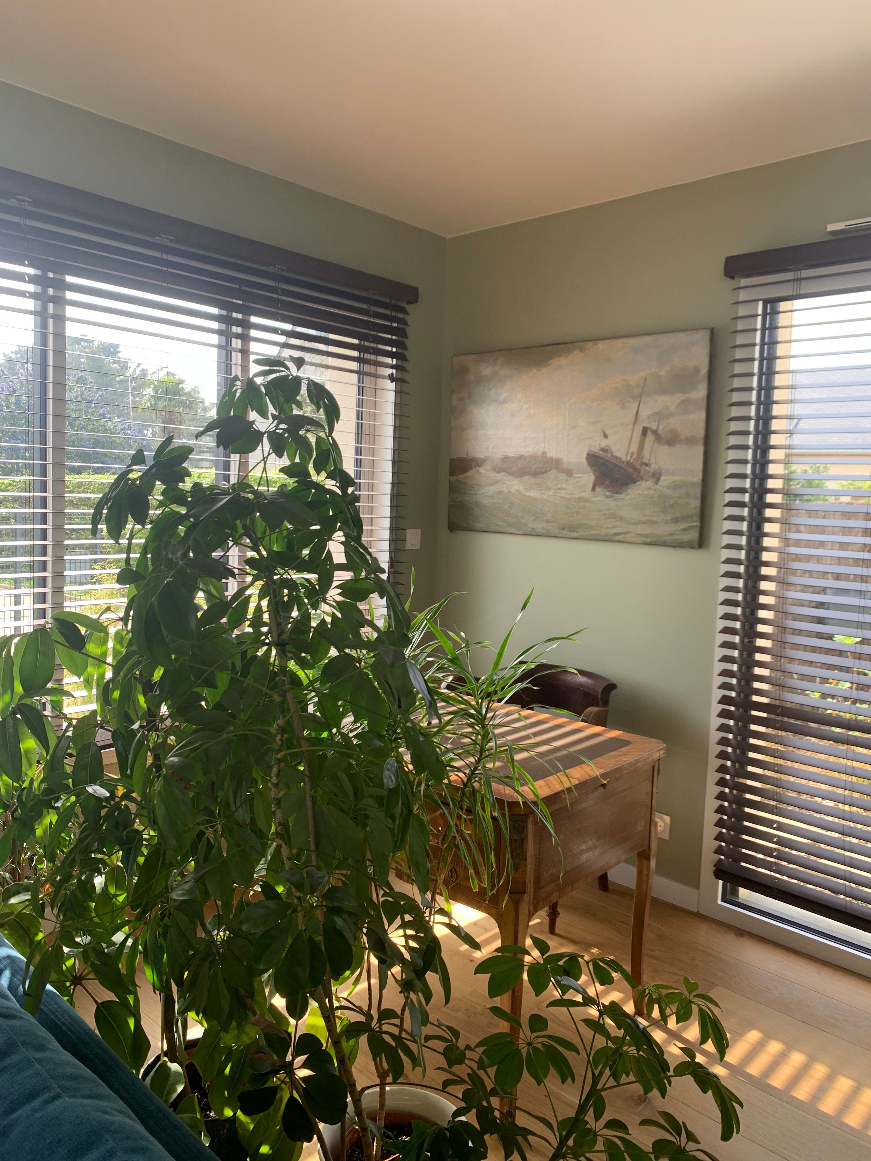 Una habitación con ventanas amplias, una mesa de madera y un cuadro en la pared.