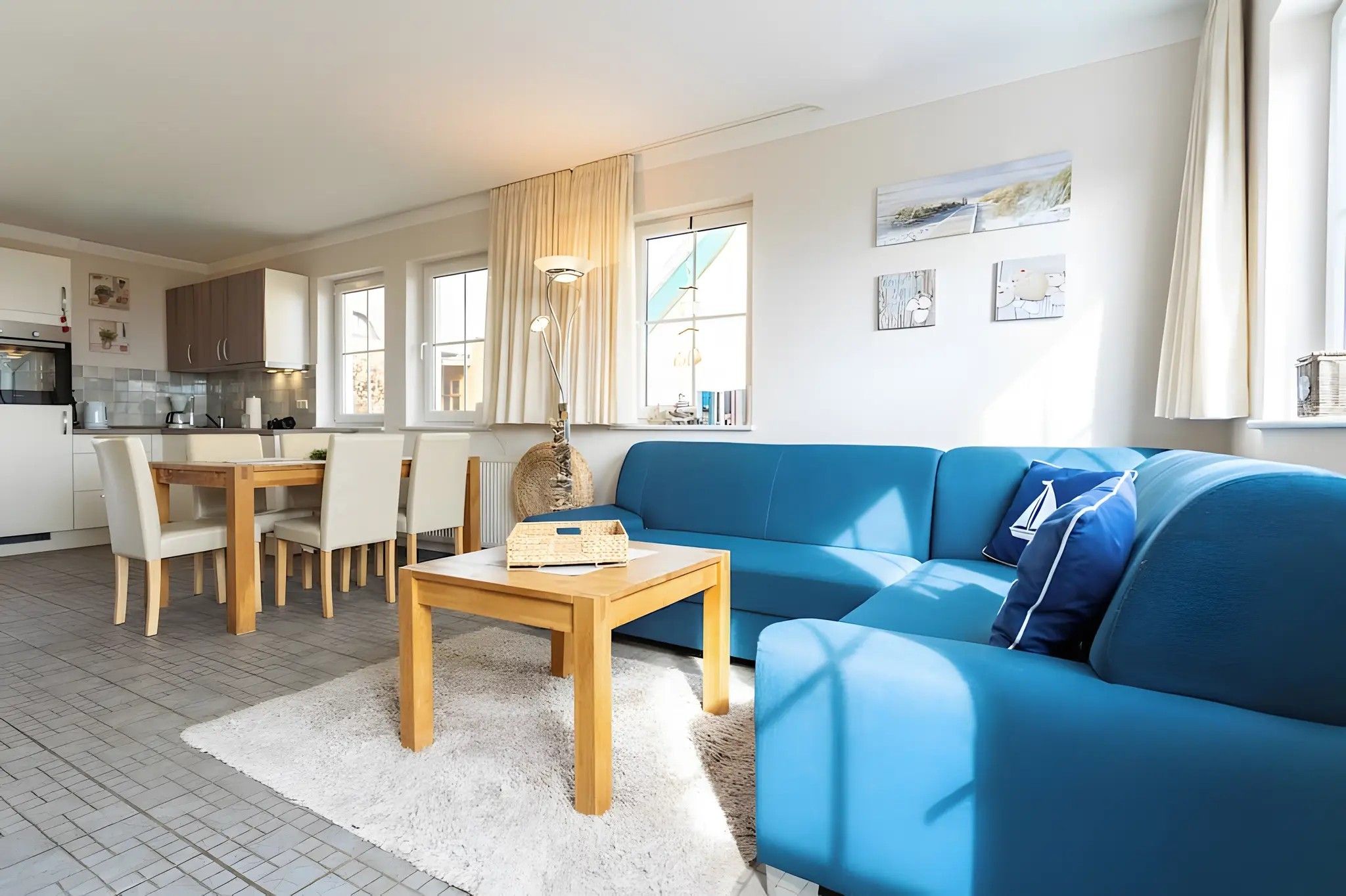 En moderne stue med en blå sofa, et træbord og et spiseområde med stole.