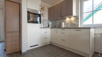 A modern kitchen with white cabinets, a built-in oven, and a window providing natural light.