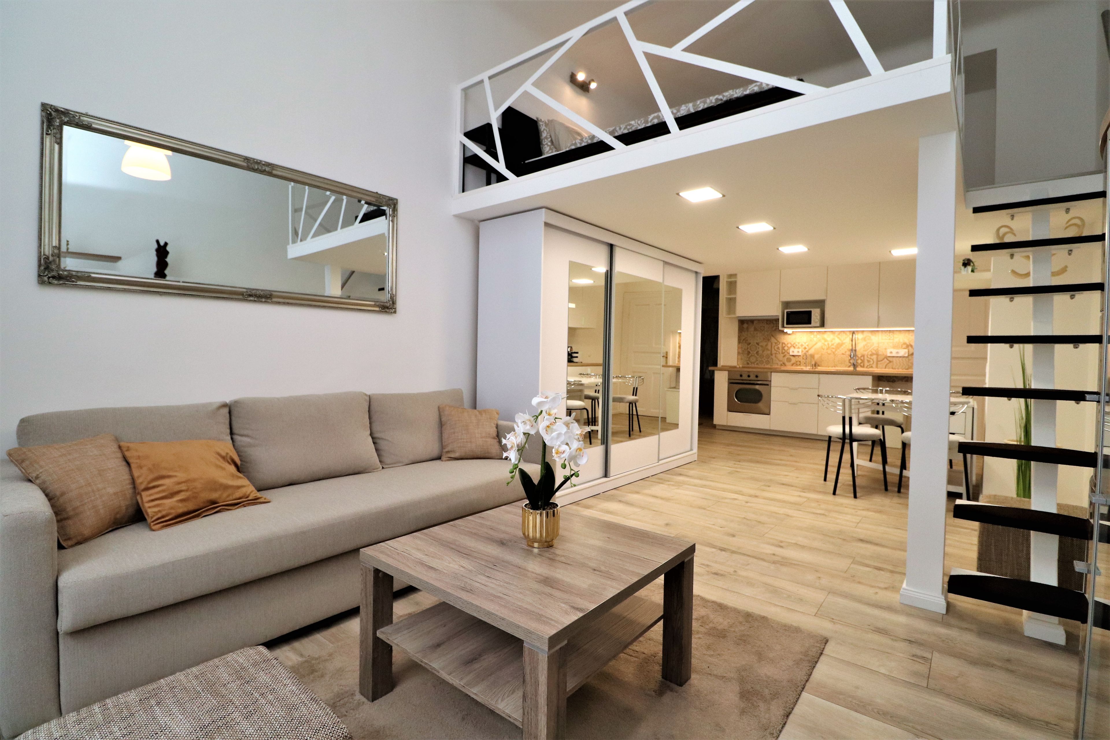 A modern living room with a sofa, a coffee table, and a mirror.