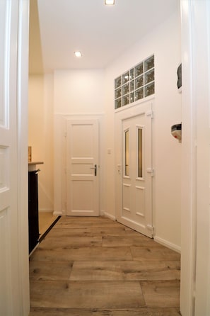 A hallway with wooden flooring, white doors, and a small window with frosted glass. - Roxy Stúdió 4A - Budapest (Budapest)
