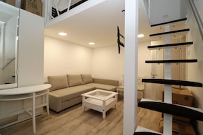 A modern living room with a sectional sofa, a coffee table, and a white TV stand. - Roxy Stúdió 4A - Budapest (Budapest)