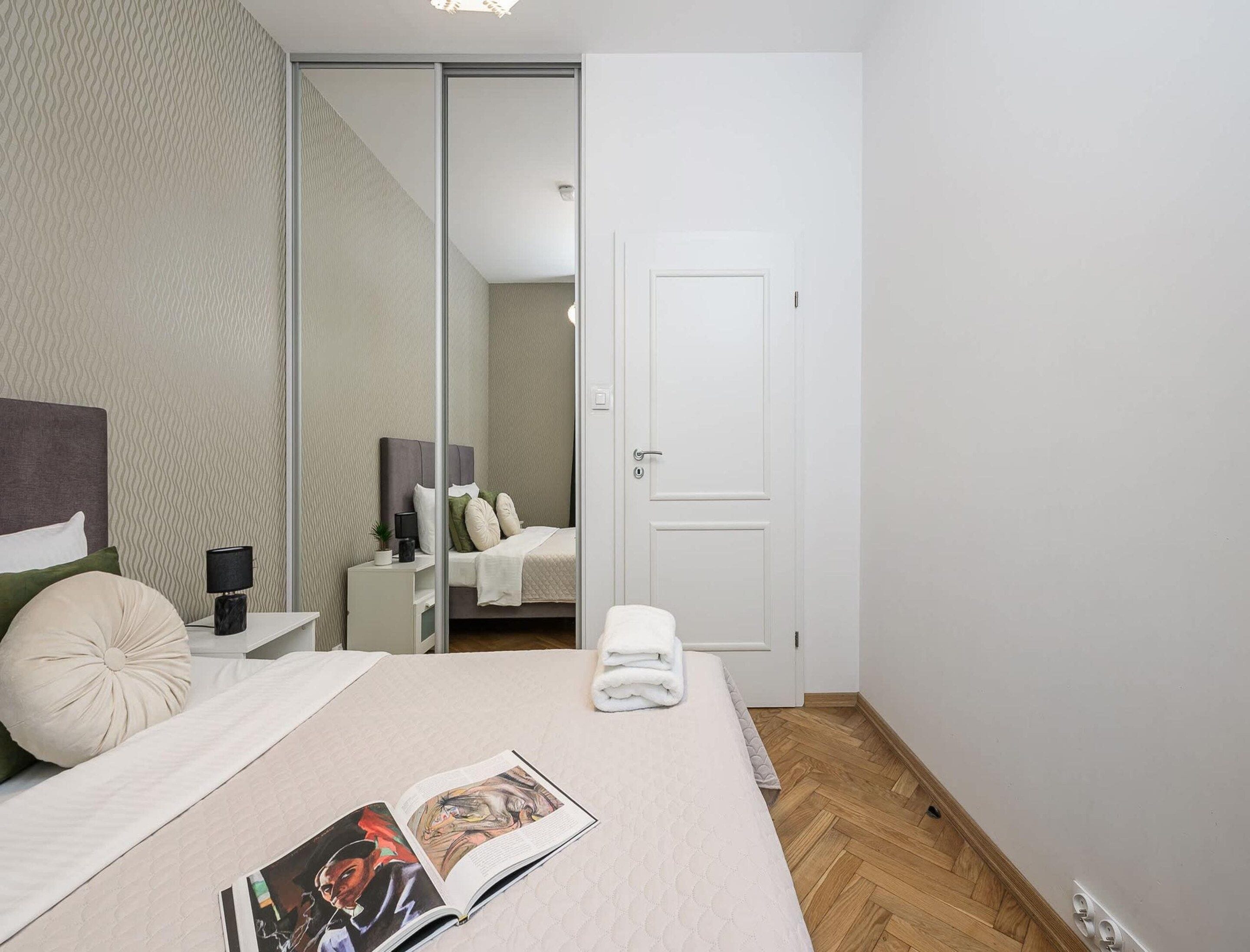 A modern bedroom with a bed, bedside table, and a mirror.
