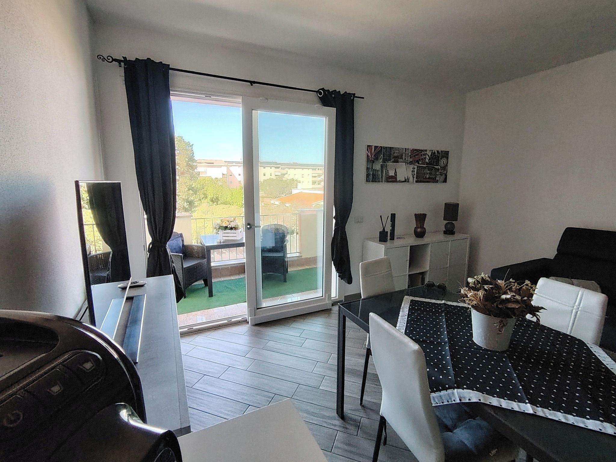 Un soggiorno moderno con zona pranzo, un balcone vista e un tavolino con un vaso.