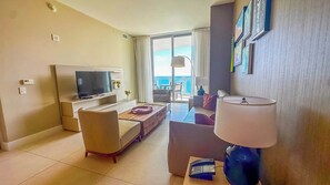 A modern living room with a flat-screen TV, a sofa, a coffee table, and a lamp. - Iconic 1 Bedroom Hollywood Sky Penthouse (Hollywood)