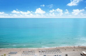 A beach with rows of sun loungers and umbrellas, a lifeguard tower, and a clear view of the ocean. - Iconic 1 Bedroom Hollywood Sky Penthouse (Hollywood)