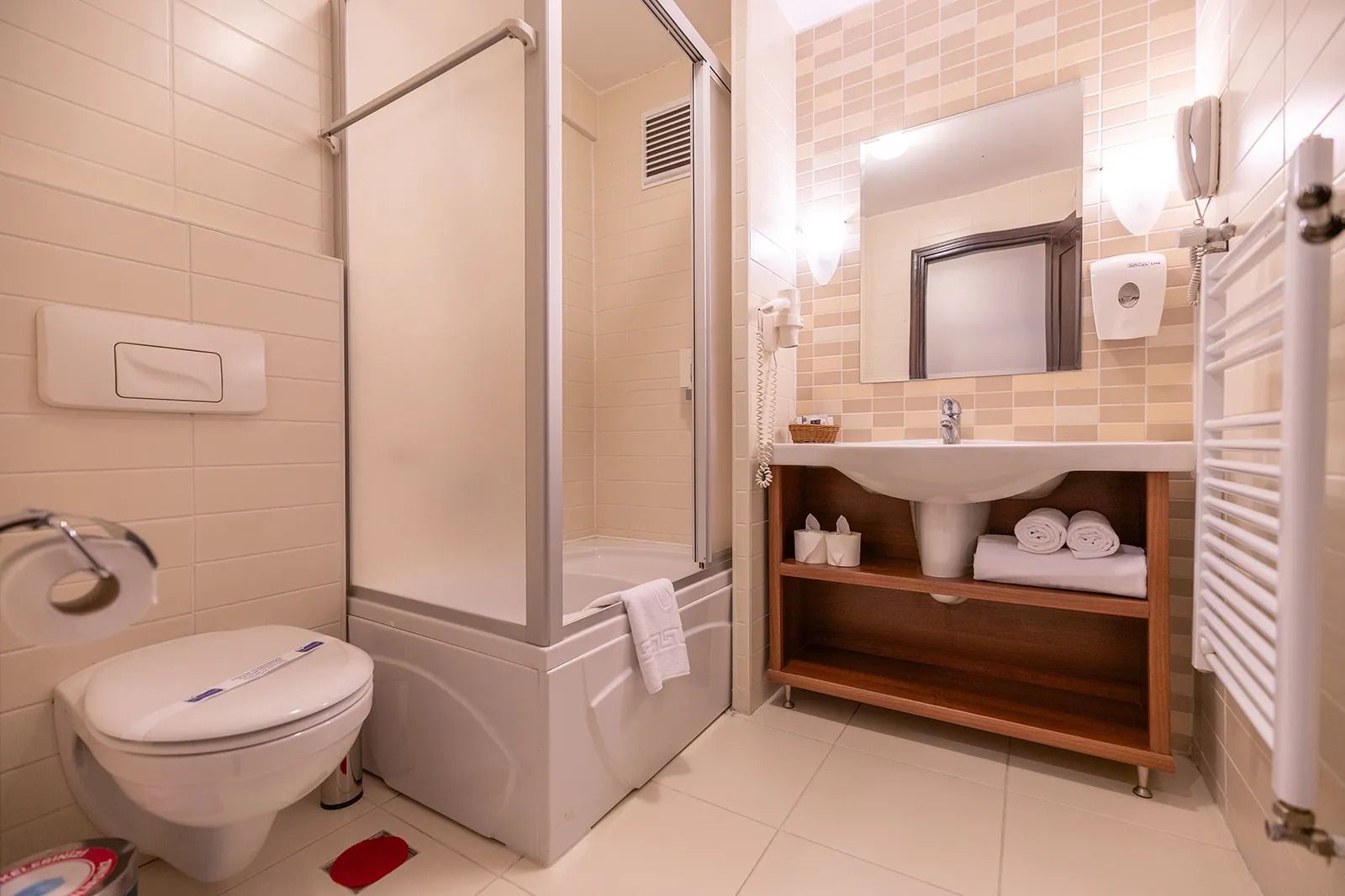 A modern bathroom with a shower, toilet, sink, and a mirror above the sink.