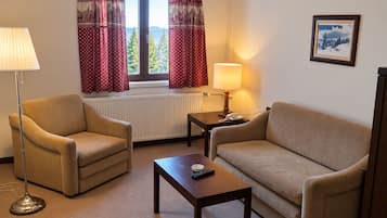 Una habitación con dos sofás, una mesa de centro, una lámpara, un teléfono y una ventana con cortinas.