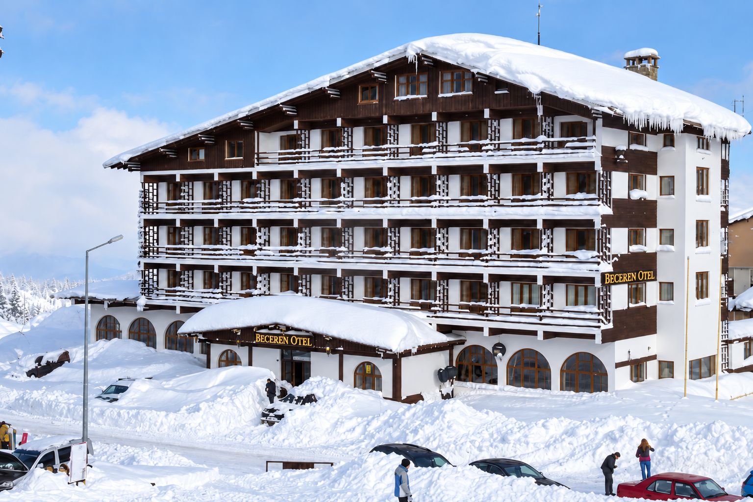 A multi-story hotel with a snow-covered roof and balconies, surrounded by snow.