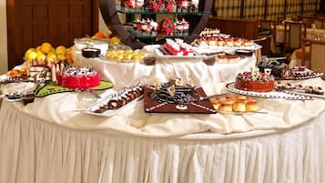 A buffet table with various desserts and fruits, a large decorative mirror, and a wooden door in the background.