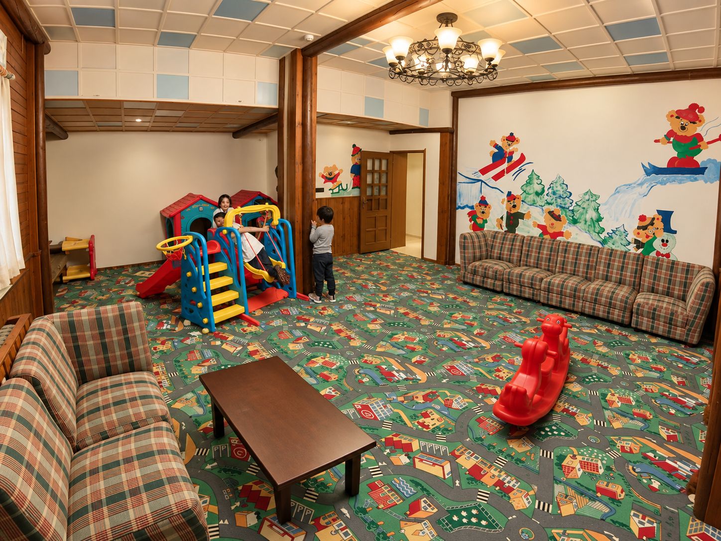 Zona de juegos infantiles con tobogán, estructura para escalar y un tapete de juego colorido.
