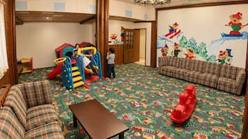 Zona de juegos infantiles con tobogán, estructura para escalar y un tapete de juego colorido.