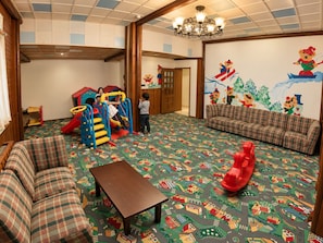 Zona de juegos infantiles con tobogán, estructura para escalar y un tapete de juego colorido.