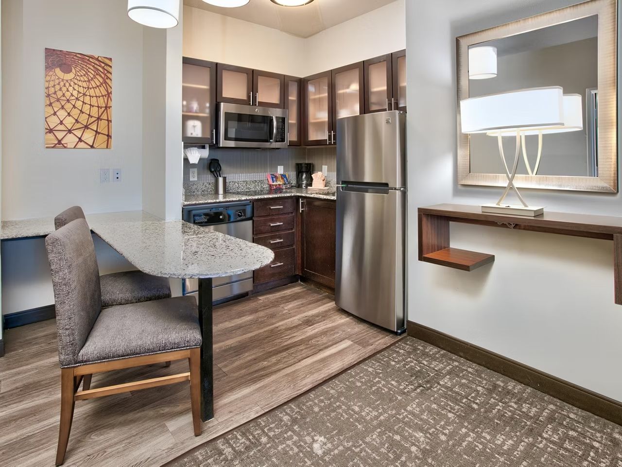 A modern kitchen with a stainless steel refrigerator, microwave, and granite countertop.