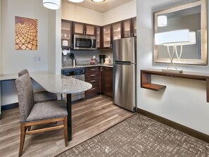 A modern kitchen with a stainless steel refrigerator, microwave, and granite countertop.