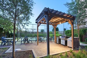 Eine Außenpatio mit Pergola, Grillstation und Sitzbereich.