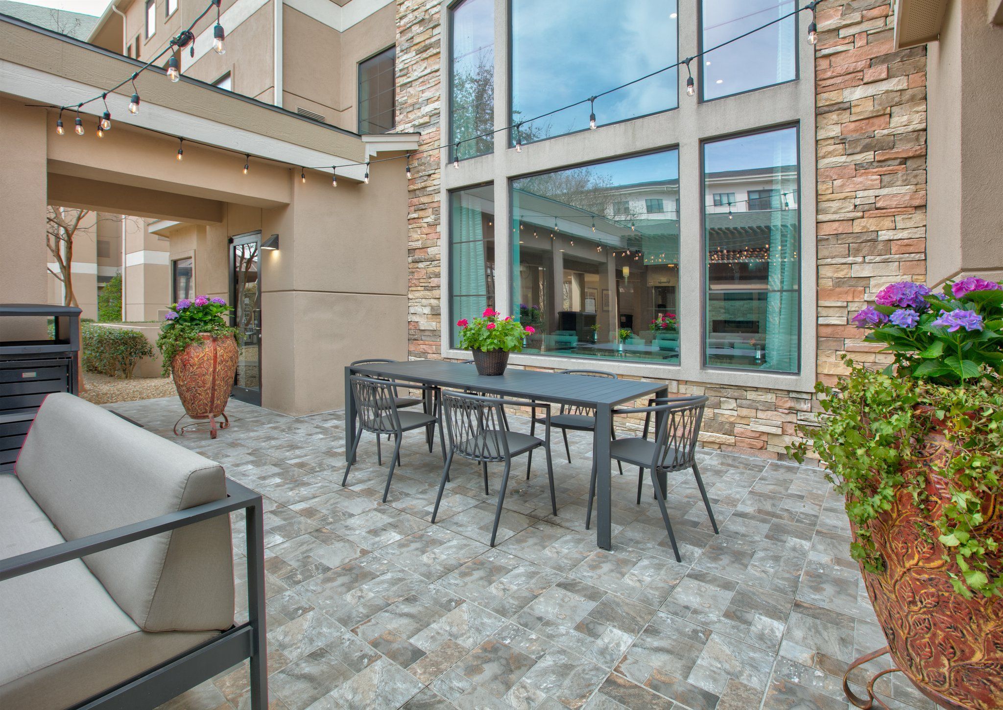 Eine Terrasse mit Tisch, Stühlen, Kübelpflanzen und einem Fliesenboden.