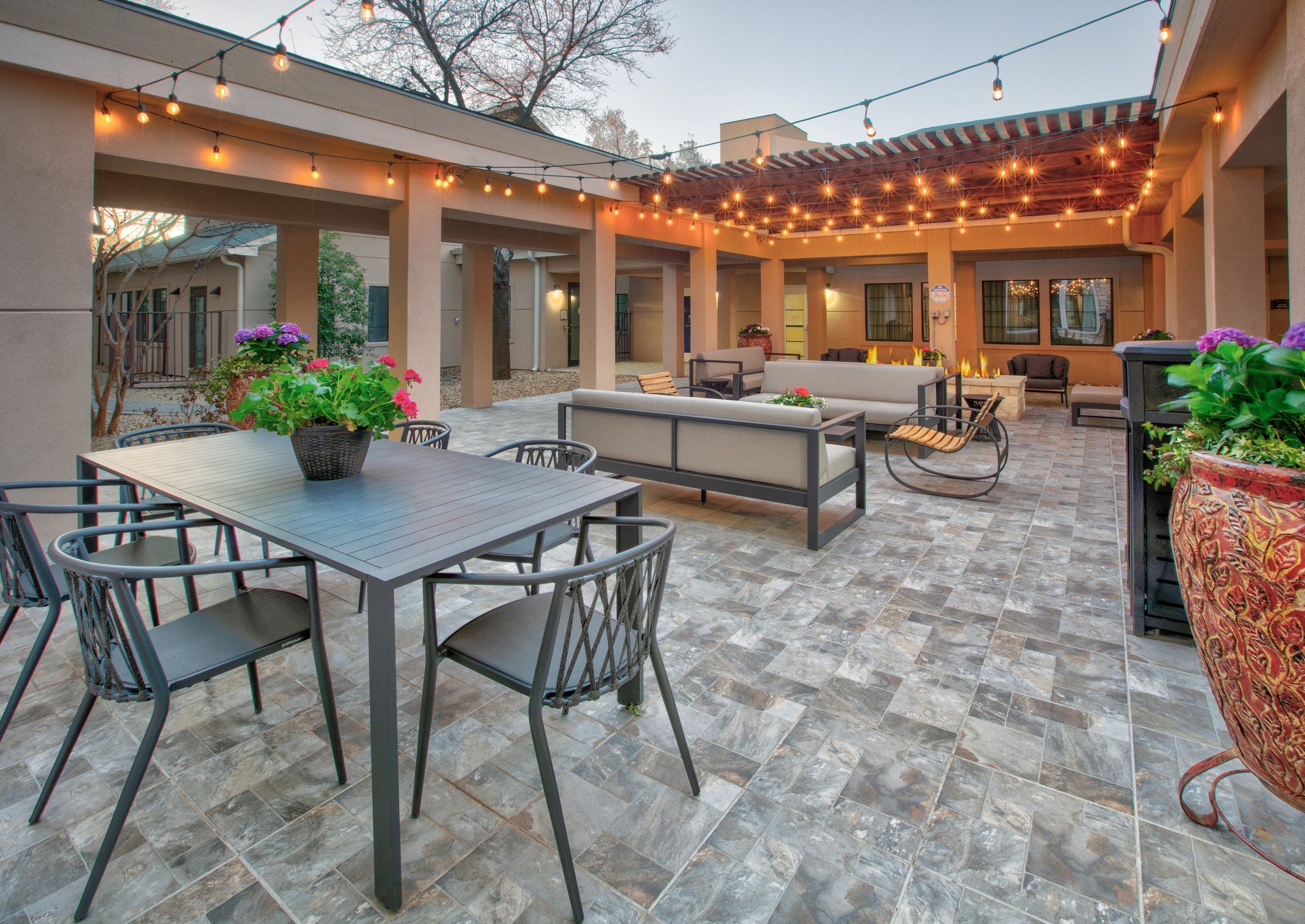 An outdoor patio with a table and chairs, a sofa, and string lights.