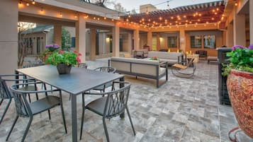 An outdoor patio with a table and chairs, a sofa, and string lights.