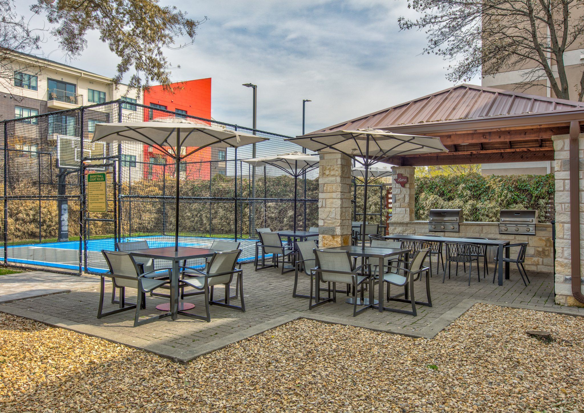 An outdoor patio area with tables and chairs, a barbecue grill, and a pool.