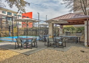 Un espace extérieur aménagé en terrasse, avec des tables et des chaises, un barbecue et une piscine.