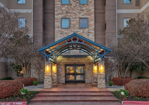A hotel entrance with a stone facade, a blue decorative arch, and a fire lane sign. - Accessible 1BR 2 Double Suite w/ Breakfast + Pool (Plano)