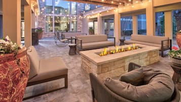 An outdoor patio with stone flooring, a fire pit, and wicker furniture.