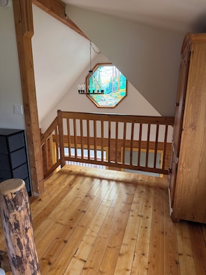 Una scala in legno con ringhiera, pavimento in legno e una finestra con vetrate artistiche.