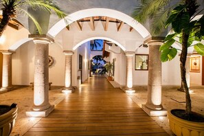 A corridor with arches and columns, leading to a room with a view of palm trees. - Magnificent Canal House w/ Dock & Adjacent Golf (Nuevo Vallarta)