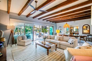 A spacious living area with a wooden ceiling, a large sofa, a coffee table, and a dining area with chairs. - Magnificent Canal House w/ Dock & Adjacent Golf (Nuevo Vallarta)