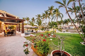 Un complexe hôtelier doté d’une terrasse, de palmiers et d’une pelouse bien entretenue.